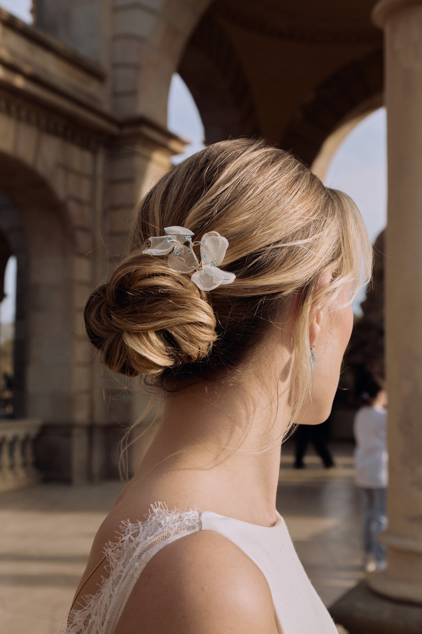 Femme de dos avec un chignon agrémenté dr pic à cheveux en organza type fleur