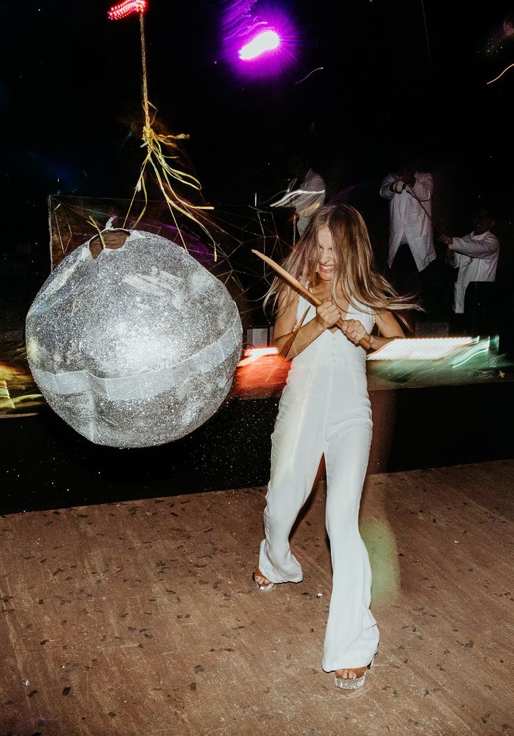 La mariée s’amusant à frapper une piñata, incarnant une idée originale de mariage et un rituel moderne, tout en apportant une touche ludique aux traditions.