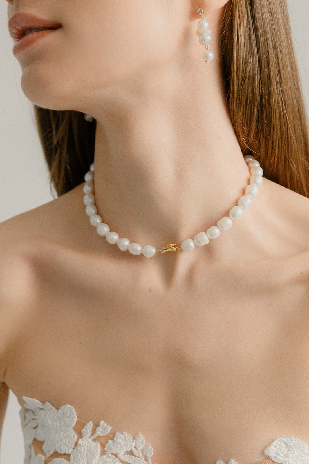 mariée portant une robe de mariage avec de la dentelle et un collier de perles naturelles