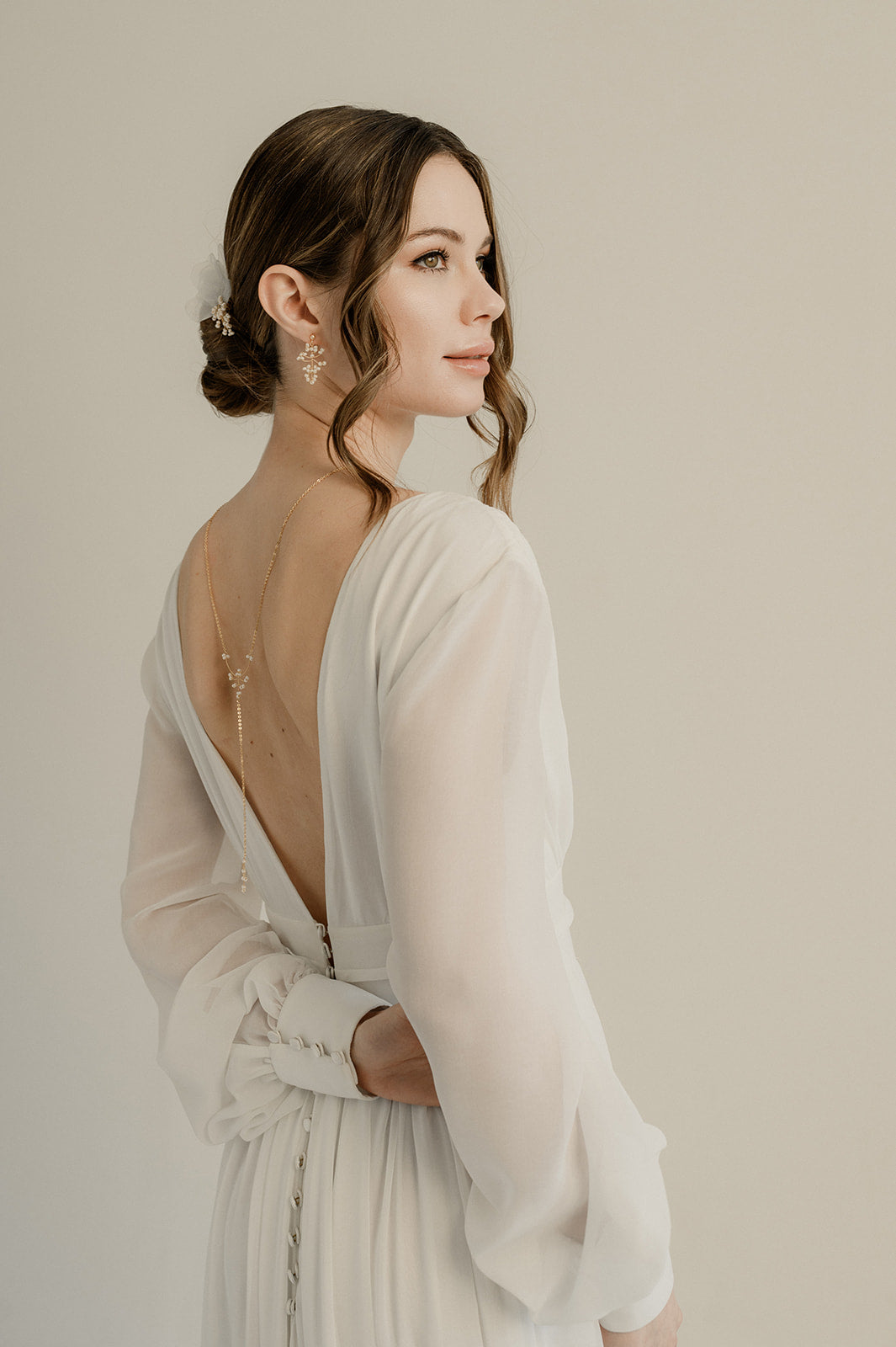 Femme de profil se tenant le bras avec sa parure de bijoux pour mariée en perles rocaille apparente