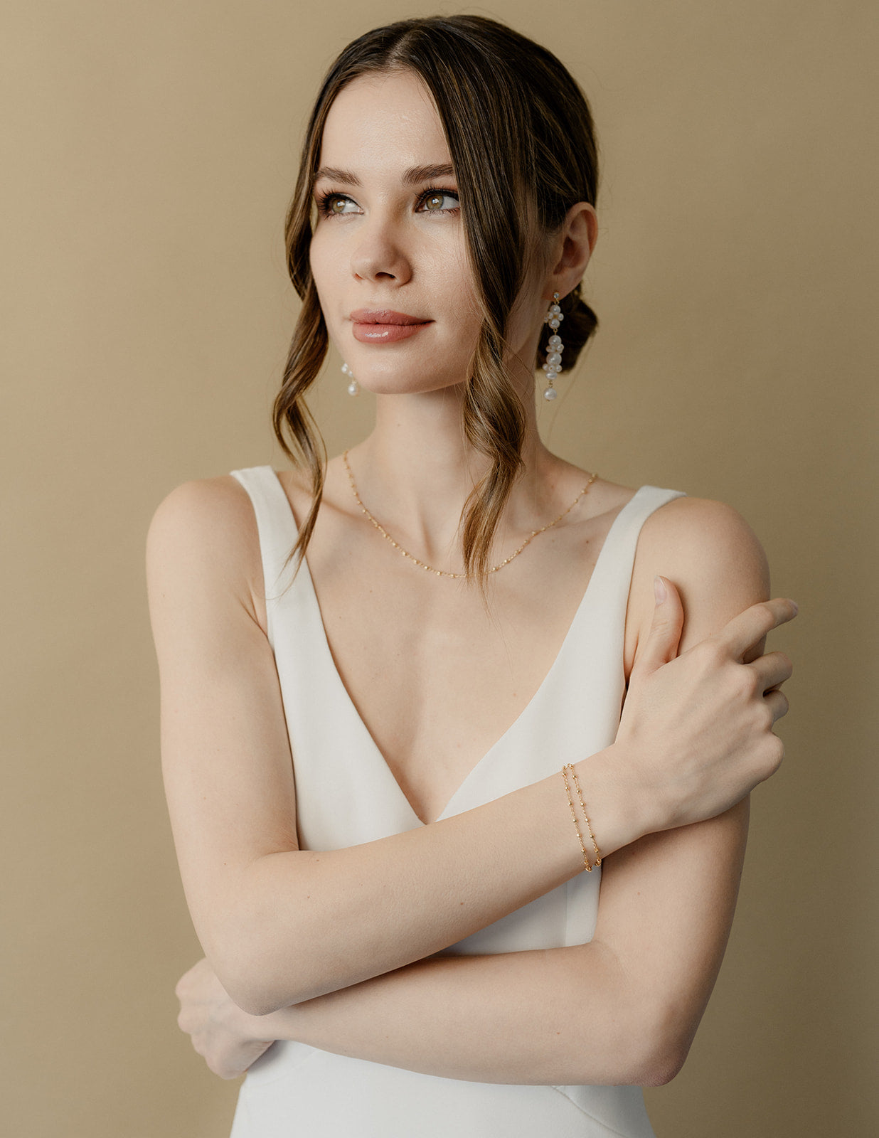 Femme entrain de se toucher l'épaule portant des bijoux de mariage avec des perles naturelles