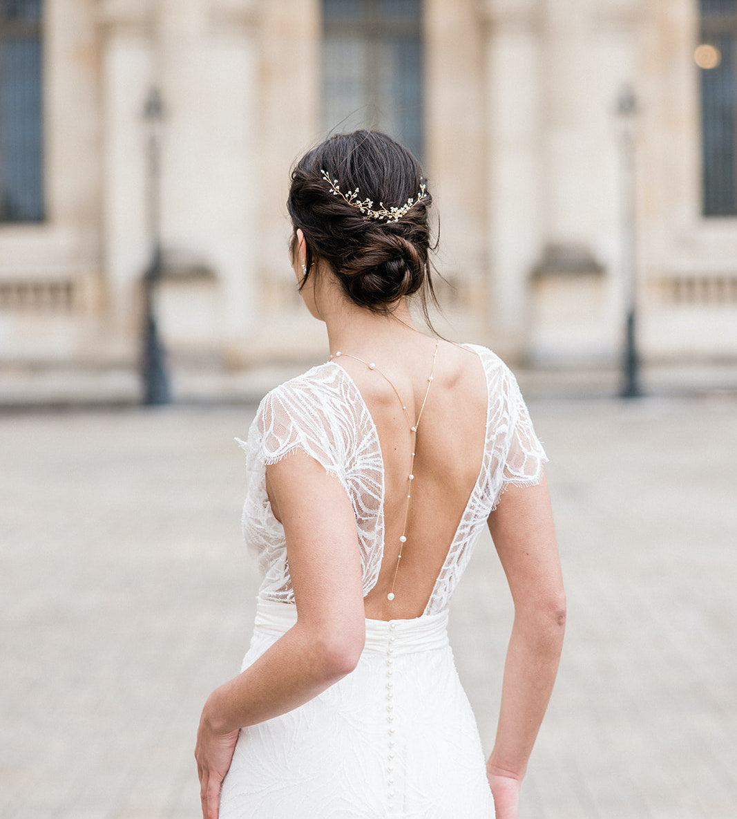 Mariée de dos portant une vigne à cheveux de mariage dorée à perles bohème et un collier de dos doré en perles