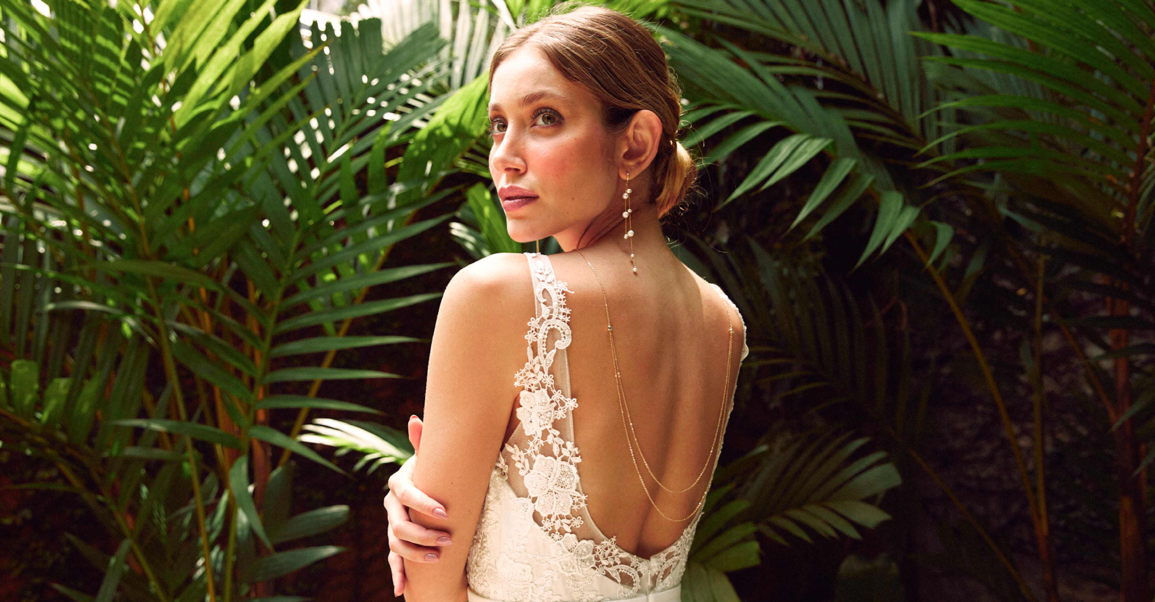 Mariée portant des boucles d'oreilles longues en perles et un collier de dos avec une robe en dentelle dos nu