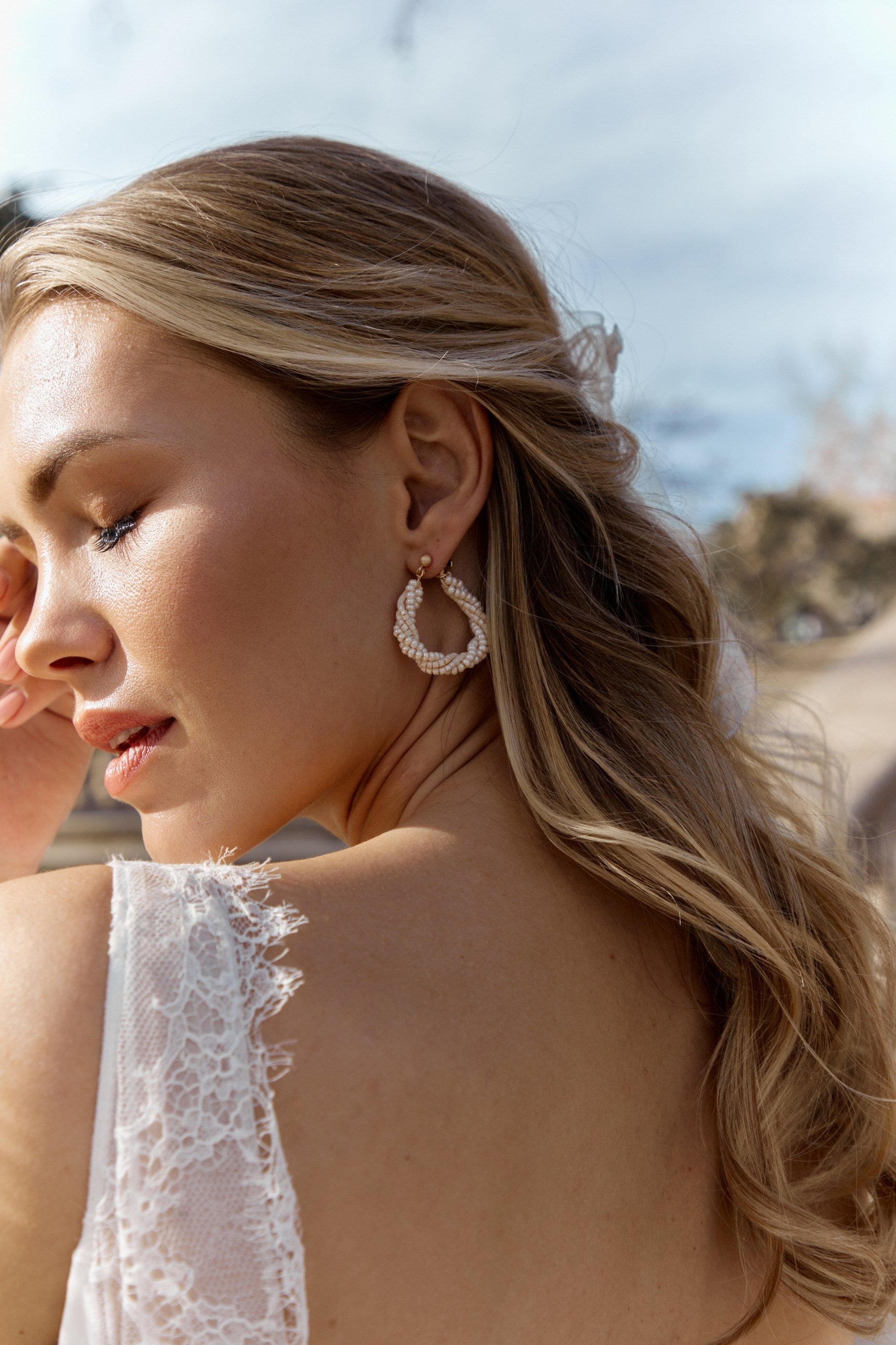 Mariée de profil montrant ses boucles d'oreilles en cercle en perles rocailles