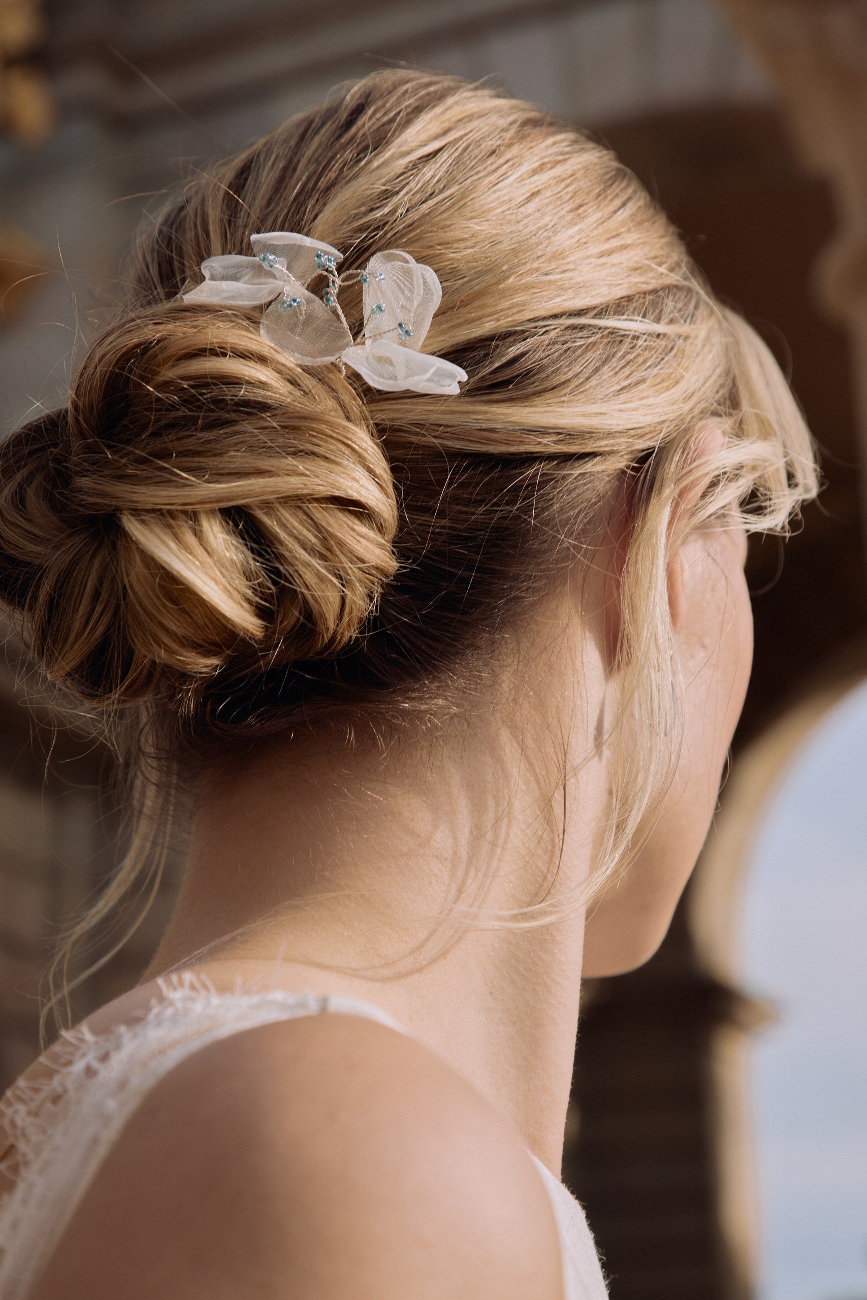 Femme de dos montrant son chignon de mariage avec des piques en organza en forme de fleur