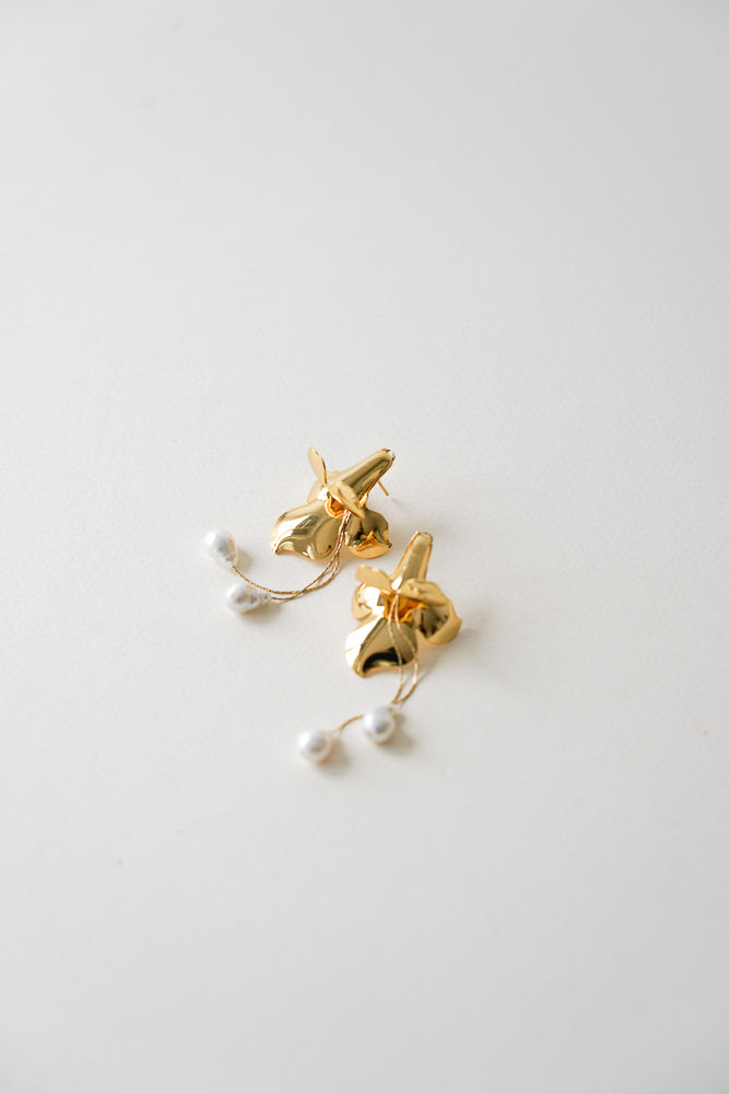 Boucles d'oreilles florales avec des perles pendantes sur un fond blanc, accessoire de mariage floral sur fond blanc