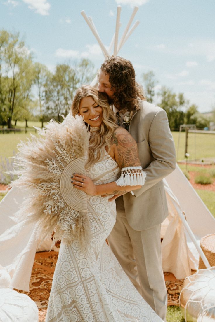 Deux mariés avec l'homme qui embrassent sa femme sur la tempe pendant qu'elle sourit son éventail avec des plumes à la main