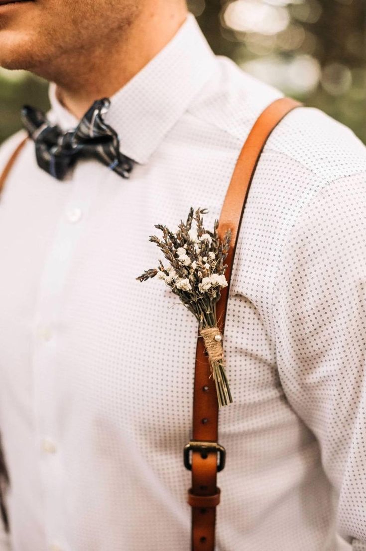 Jeune homme portant des bretelles à un mariage avec un bouquet de fleur séchée comme accessoire