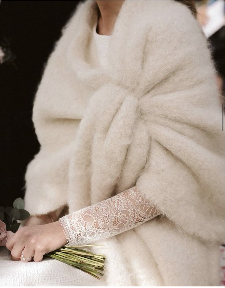 Mariée de près avec un chale en laine lors de son mariage en hiver, elle porte une robe de mariée en dentelle