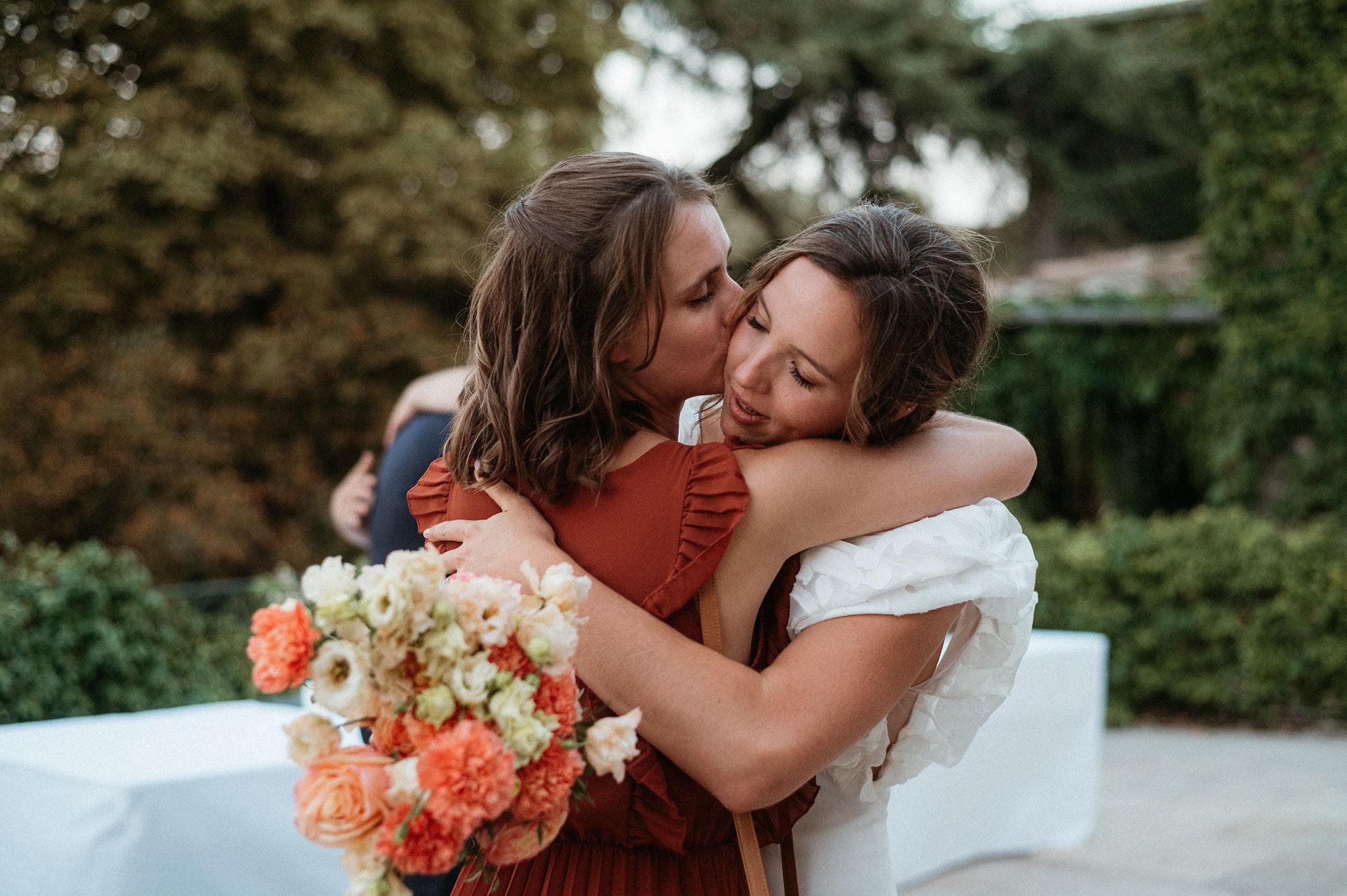 une mariée et sa témoin entre de s'enlacer le jour du mariage avec le bouquet à la main