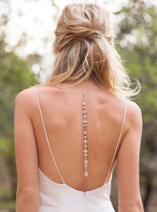 Mariée de dos portant une robe de mariage avec un grand décolleté de dos et un bijoux de dos en forme de T