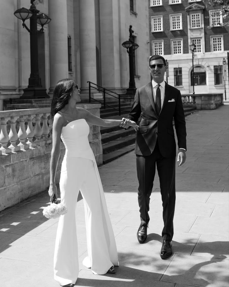 Couple heureux qui se prennent par la main, la mariée est habille d'une combinaison de mariage bustier
