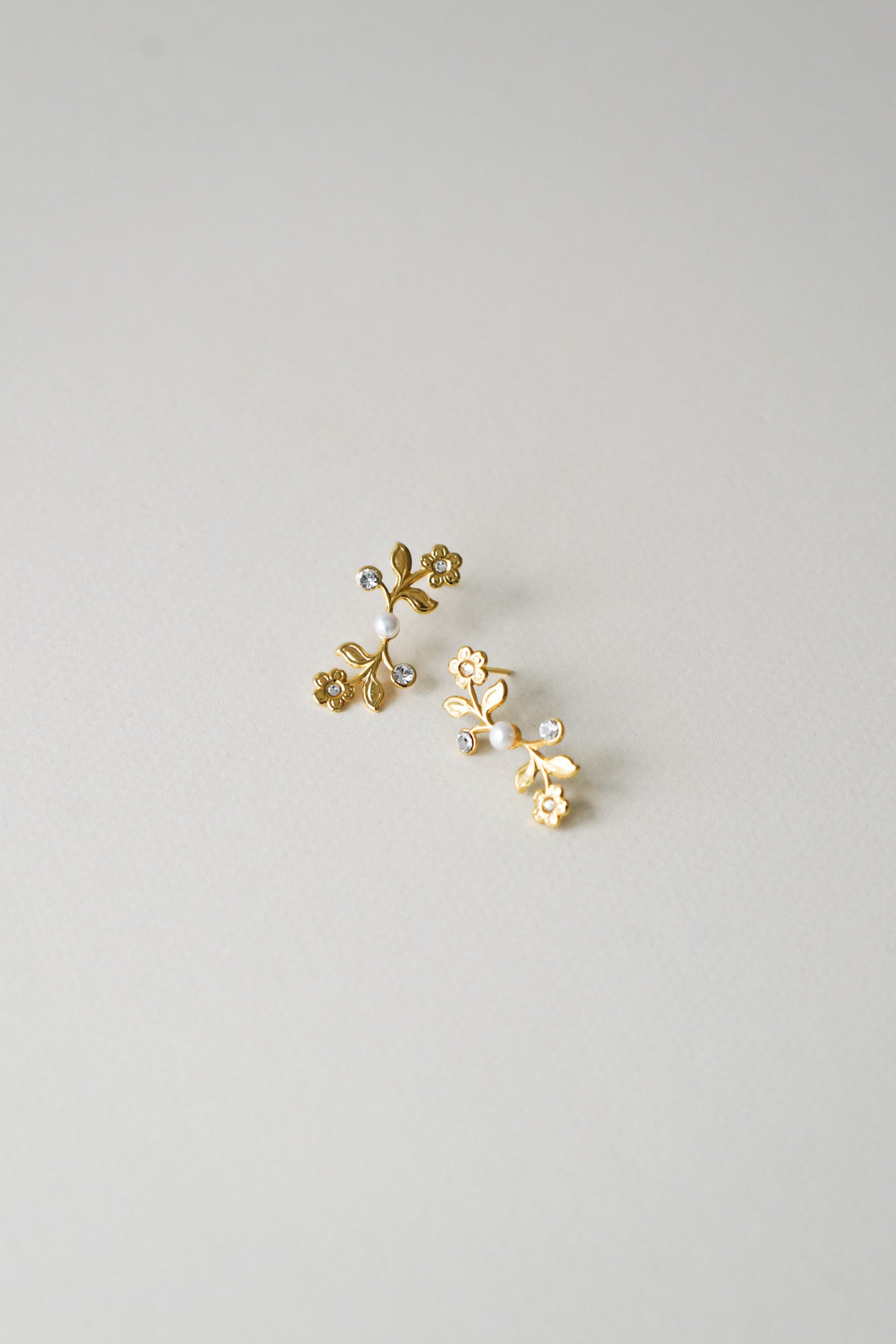 Boucles d’oreilles mi-longues délicates, composées de petites fleurs ornées en leur cœur de cristaux scintillants, et ponctuées de perles naturelles. Une création raffinée, mêlant éclat subtil et douceur florale, idéale pour une mariée romantique.