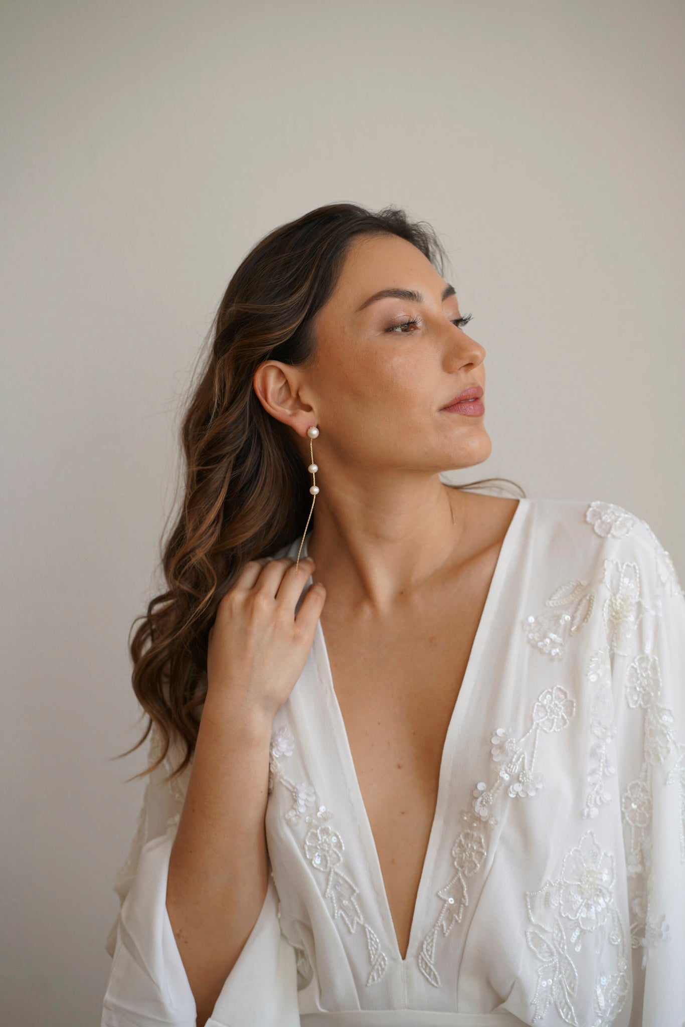 Boucles d'oreilles dorées pendantes avec 3 perles blanches portées par une mariée