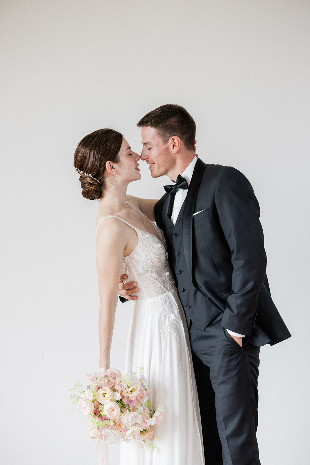 Couple de mariés, la mariée avec un chignon bas sophistiqué et des bijoux de mariage étincelants, illustrant une coiffure élégante.