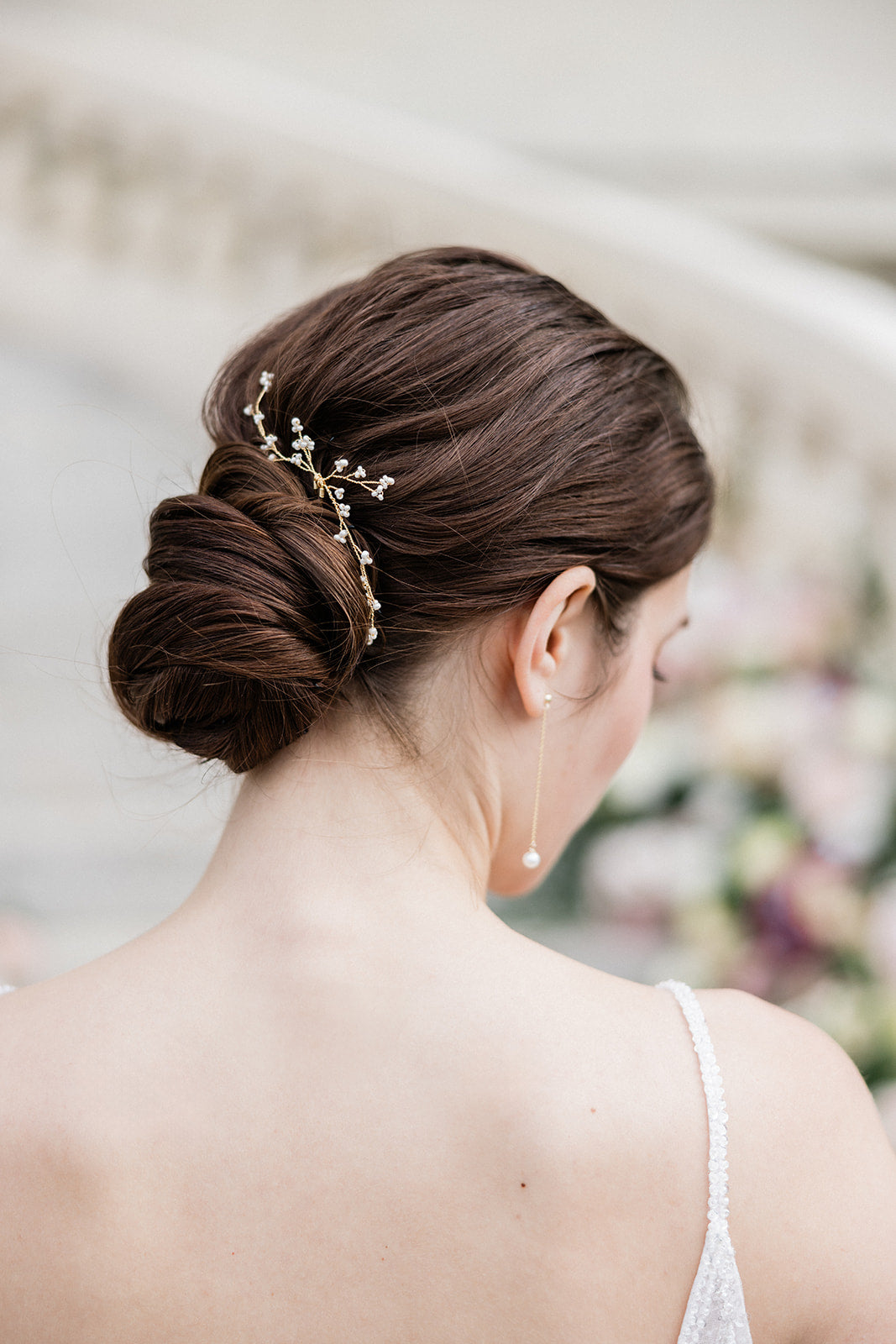 Chignon bas de mariée élégant orné de bijoux fins et délicats, ajoutant une touche de sophistication et de raffinement à la coiffure de mariage