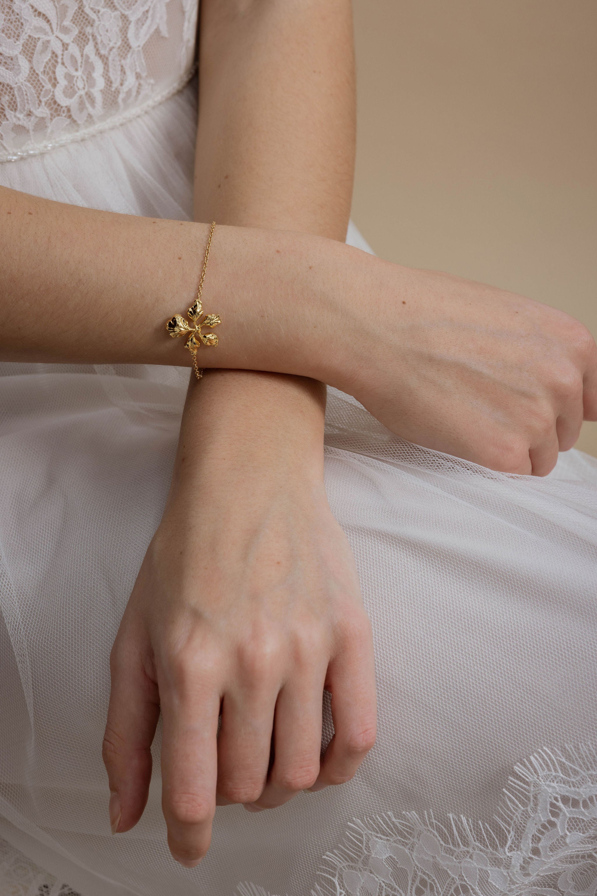 Bracelet de mariée doré au détail floral, et délicat, idéal pour sublimer une tenue de mariage romantique.