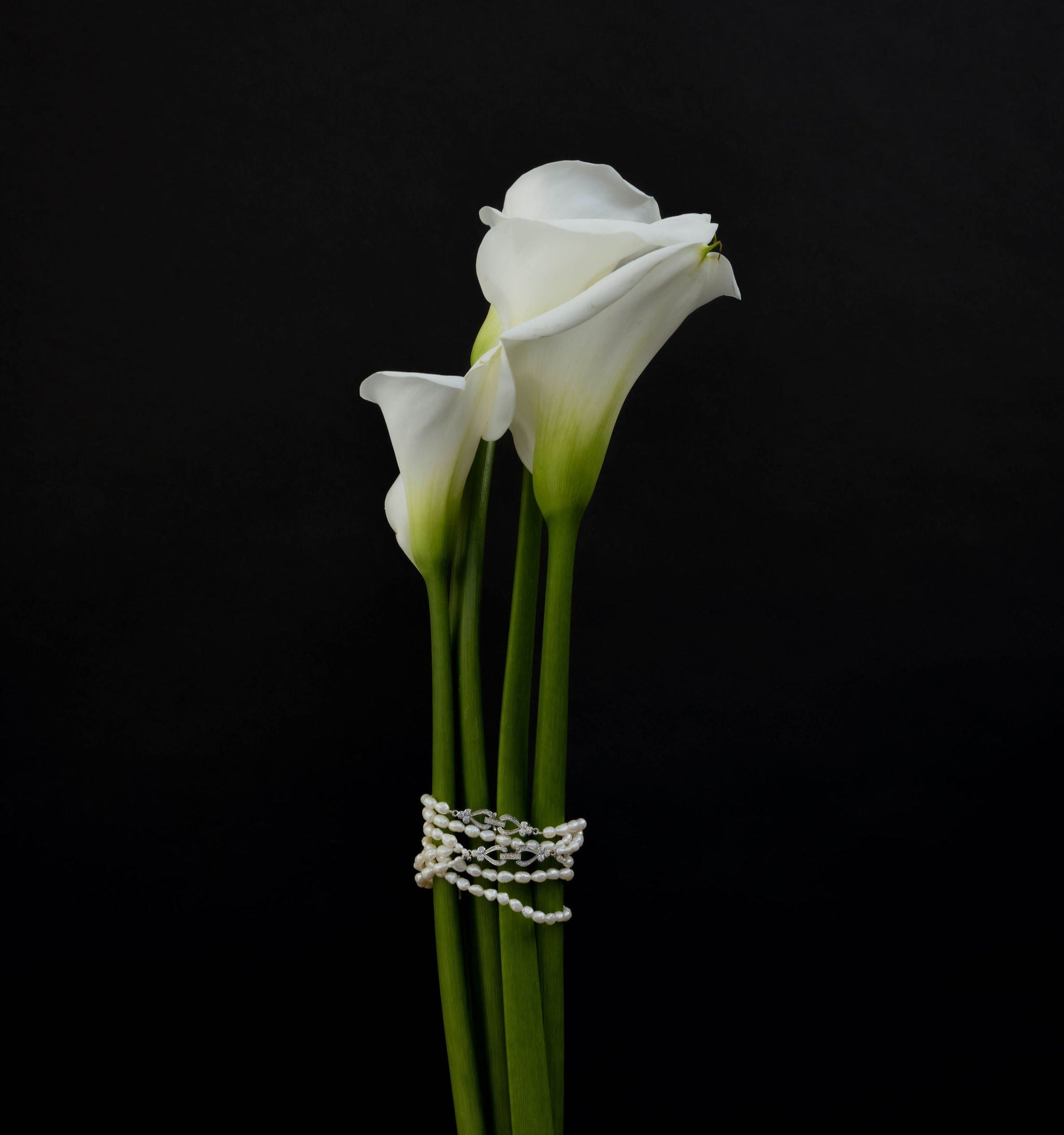 Fleur blanches sur un fond noir avec des bijoux en perles baroques