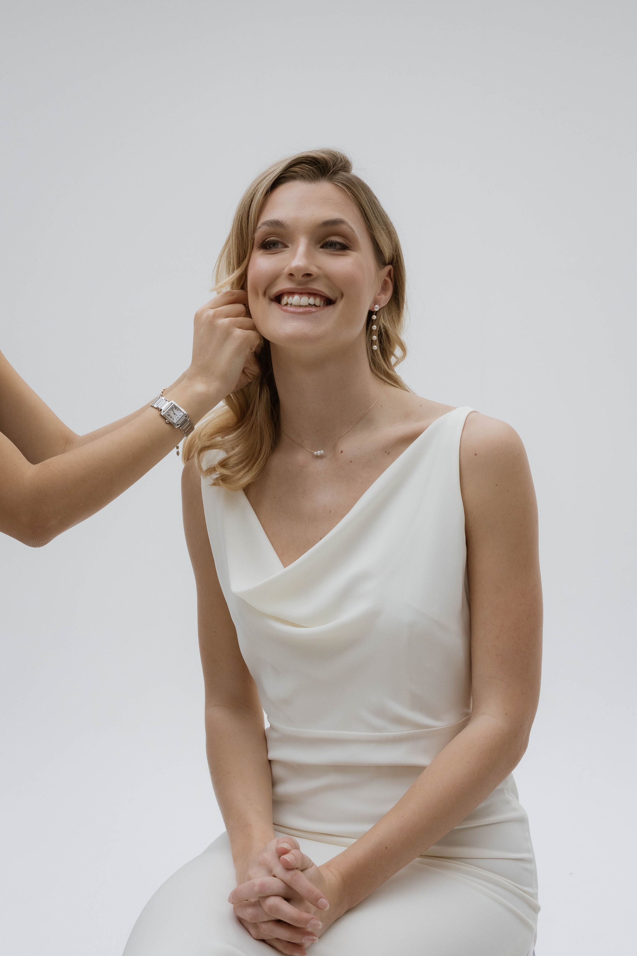 Mariée en robe blanche, la mariée porte des boucles d’oreilles en perles naturelles et un collier délicat, accompagnés de cheveux lâchés pour un style naturel et élégant