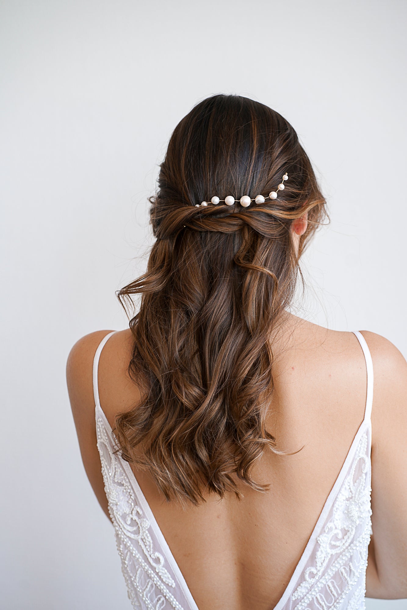 Mariée avec de beaux cheveux long bouclés au style bohème portant un pic à cheveux à neuf perles blanches
