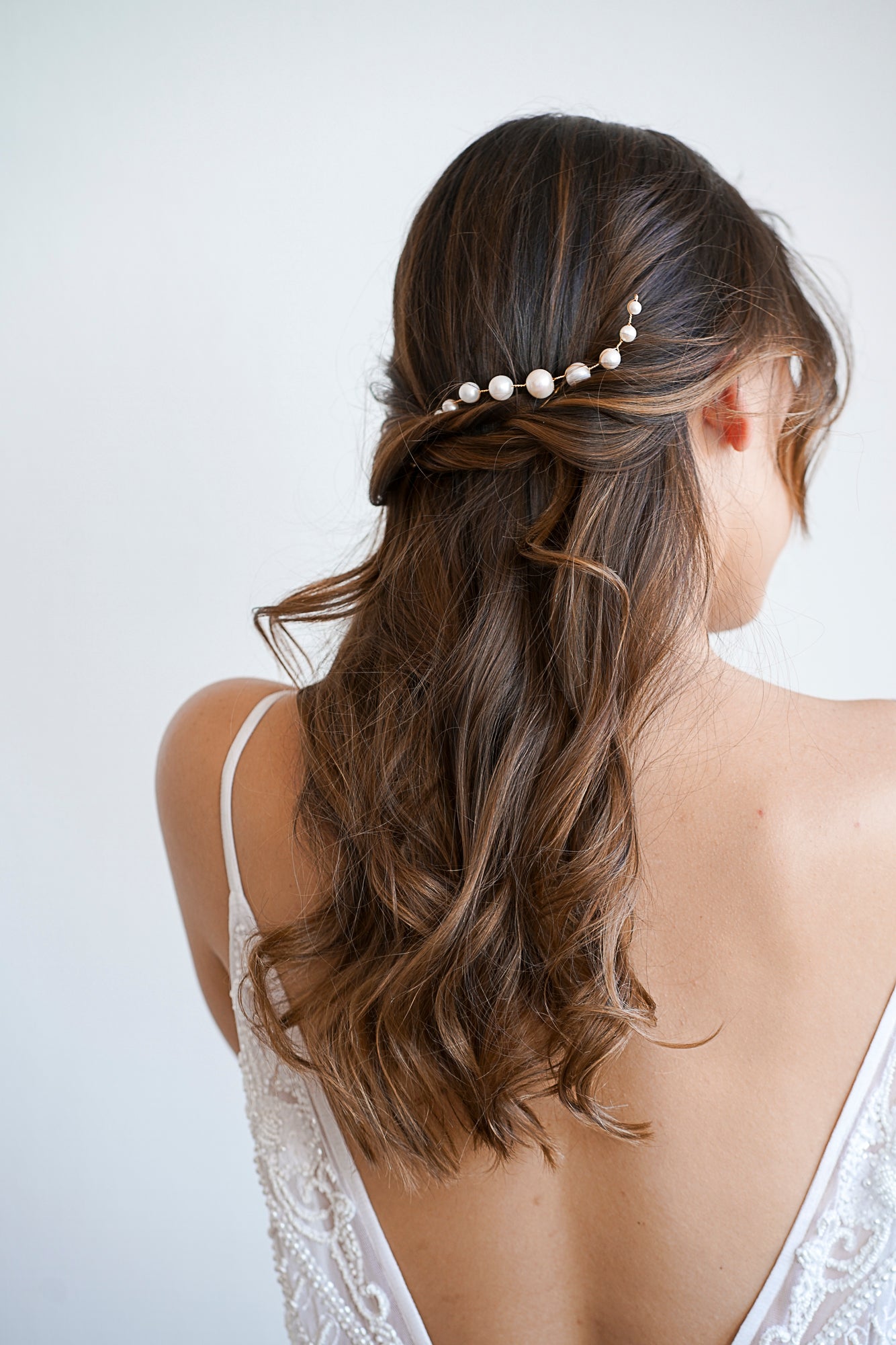 Mariée avec une coiffure bohème aux cheveux lachés portant un pic à cheveux de mariage à neuf perles blanches
