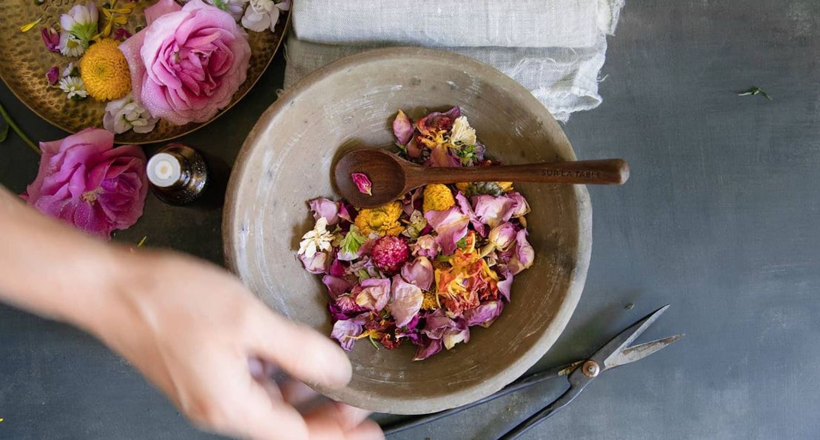fleurs séchées dans un bol avec des huiles essentielles et des ustensiles pour couper les fleurs