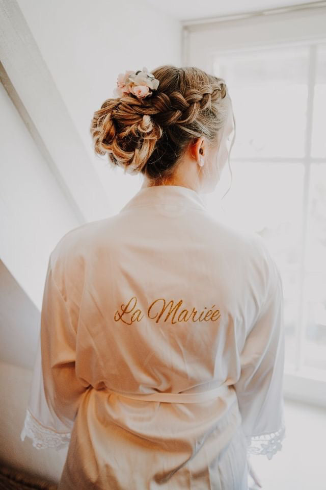 Femme de dos montrant sa coiffure tressée de mariage avec des fleurs ainsi que son kimono avec inscrit la mariée