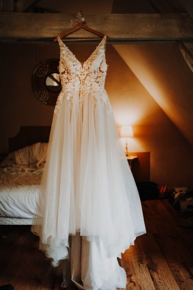 Robe de mariée avec décolleté de dos sur un cintre en hauteur dans une chambre à lumière tamisée