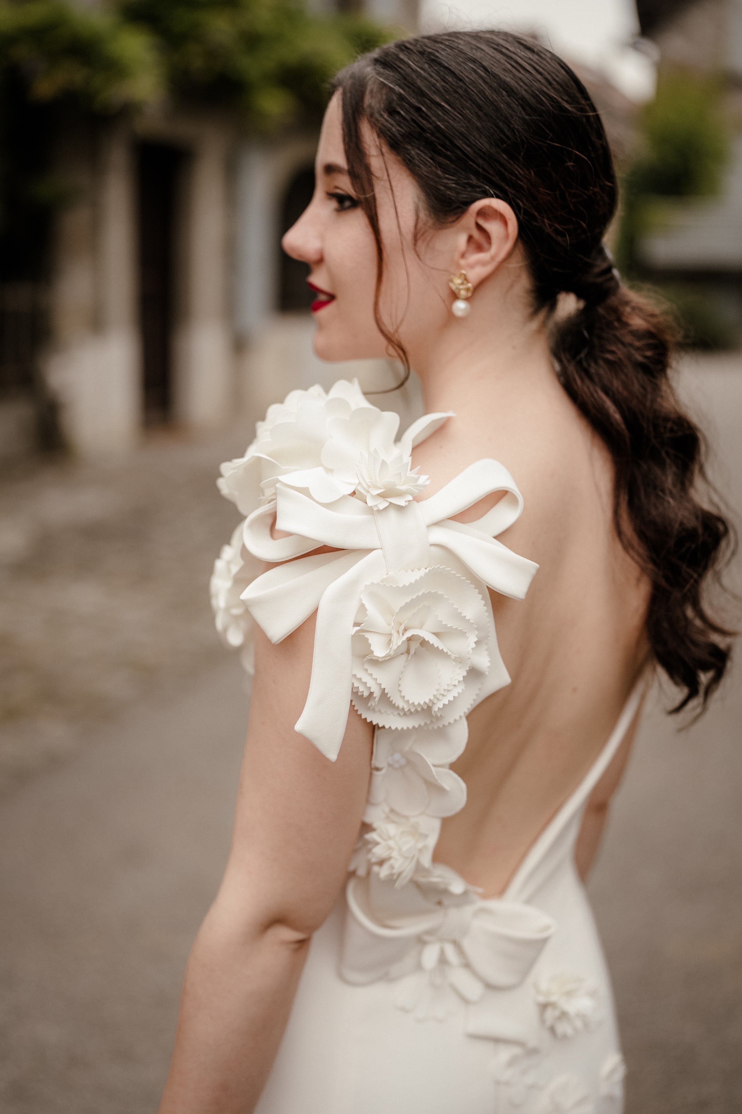 Mariee de cote avec une coiffure aux cheveux attaches et des boucles d'oreilles pendantes avec des perles de culture