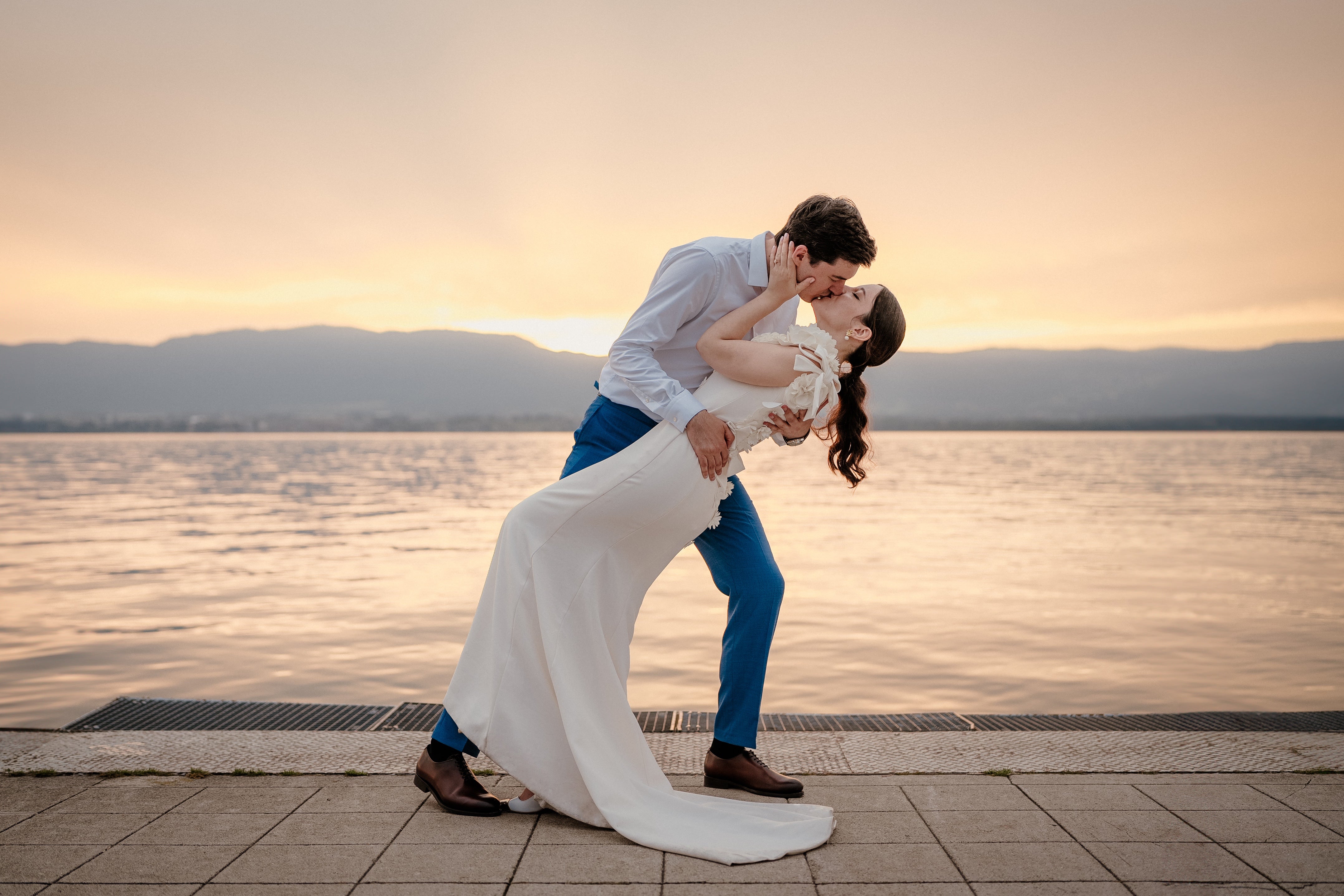 Couple de jeunes mariées qui d'embrassent au coucher du soleil près de la mer.