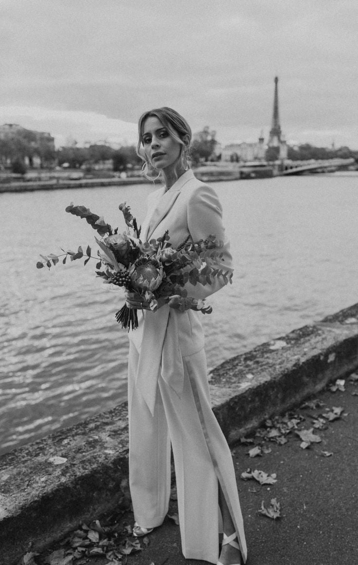 Mariée avec un bouquet a paris, elle porte un tailleur et des talons blanc et un chignon de mariage floux