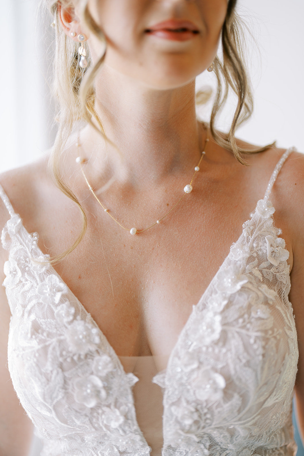 Mariee qui porte un collier en perles et une robe en dentelle