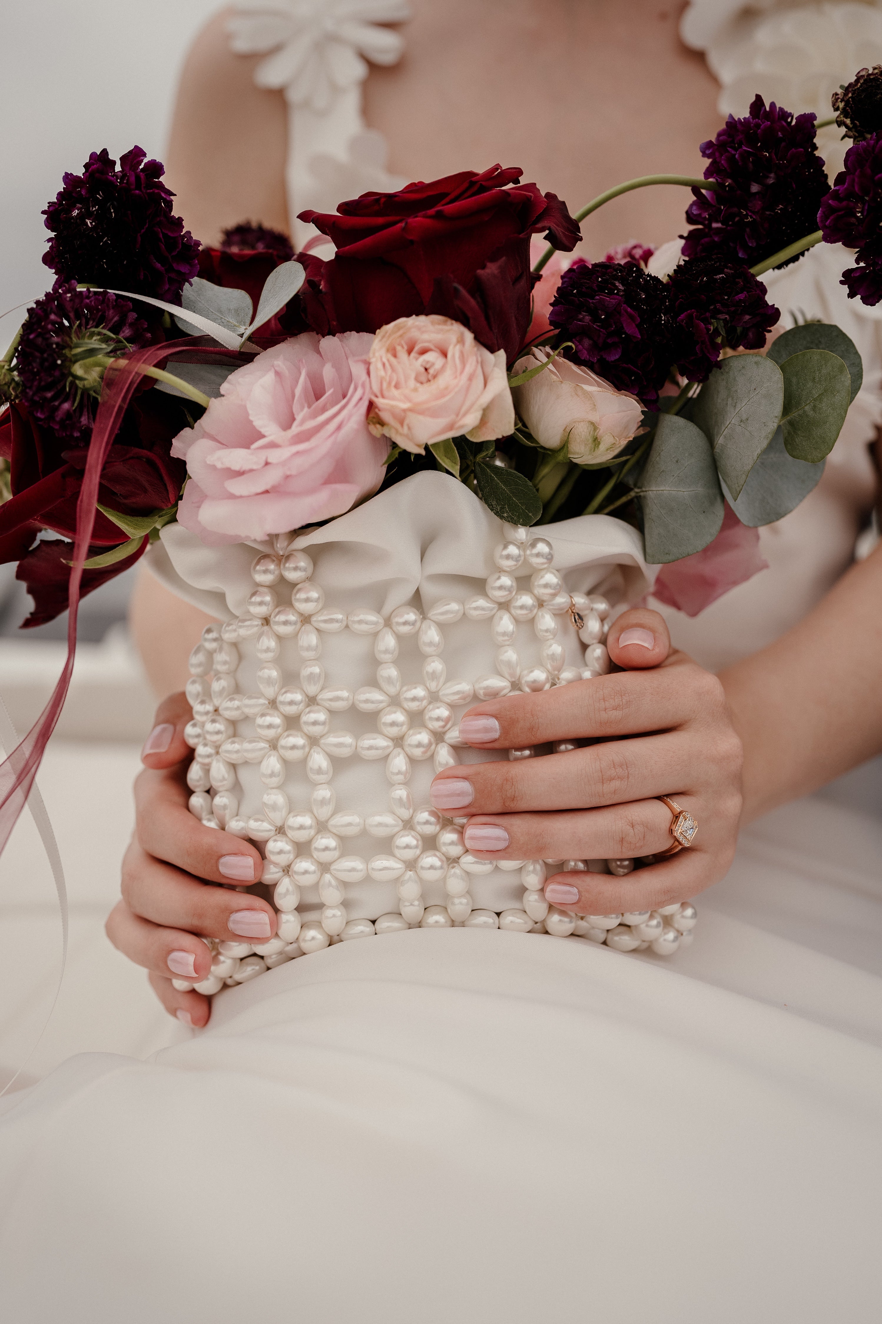 Mariée assise portant un sac en perles Atelier Lilac qui lui sert comment bouquet de mariage car les fleur sont a l'intérieur.