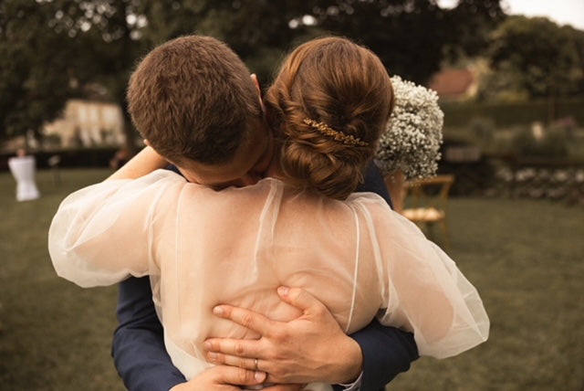Couple qui se se fait un câlin la mariée avec un chignon et un peigne de fleurs dorées