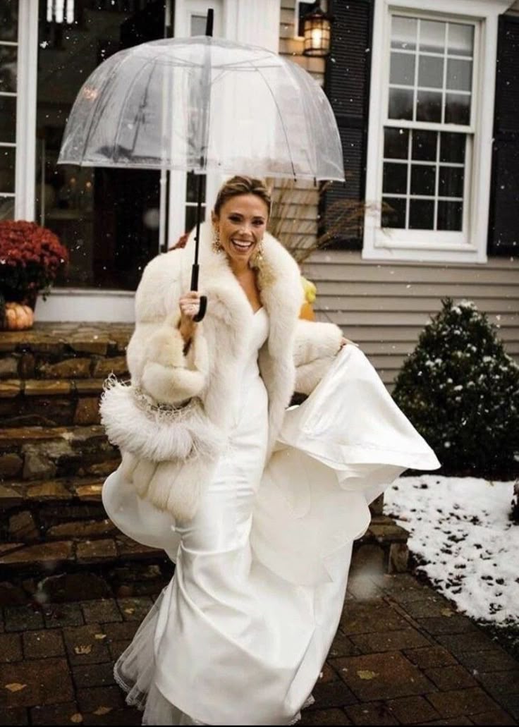 Mariée qui descend les escalier avec un parapluie en hiver, elle sourit de joie et tient sa robe de mariée avec une main
