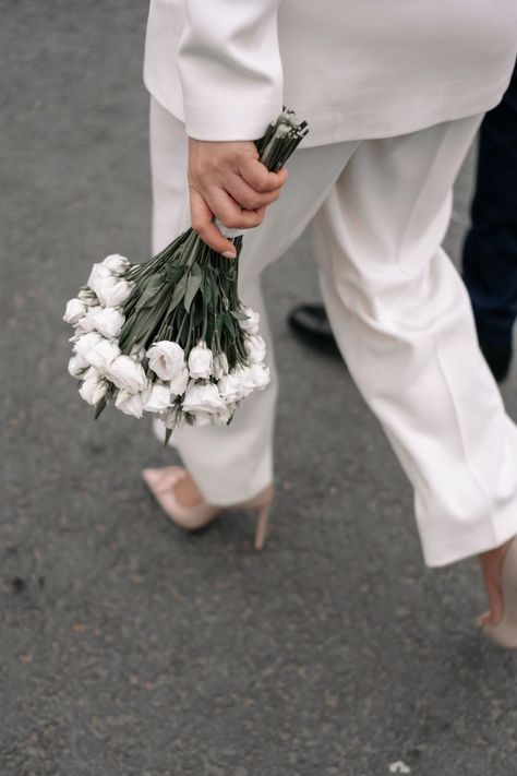 bouquet de roses blanches porte par une mariée en pantalon qui marche