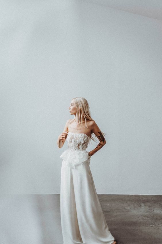 Mariée qui porte un pantalon et un corset structure avec de la dentelle, elle est blonde et a les cheveux longs detaches