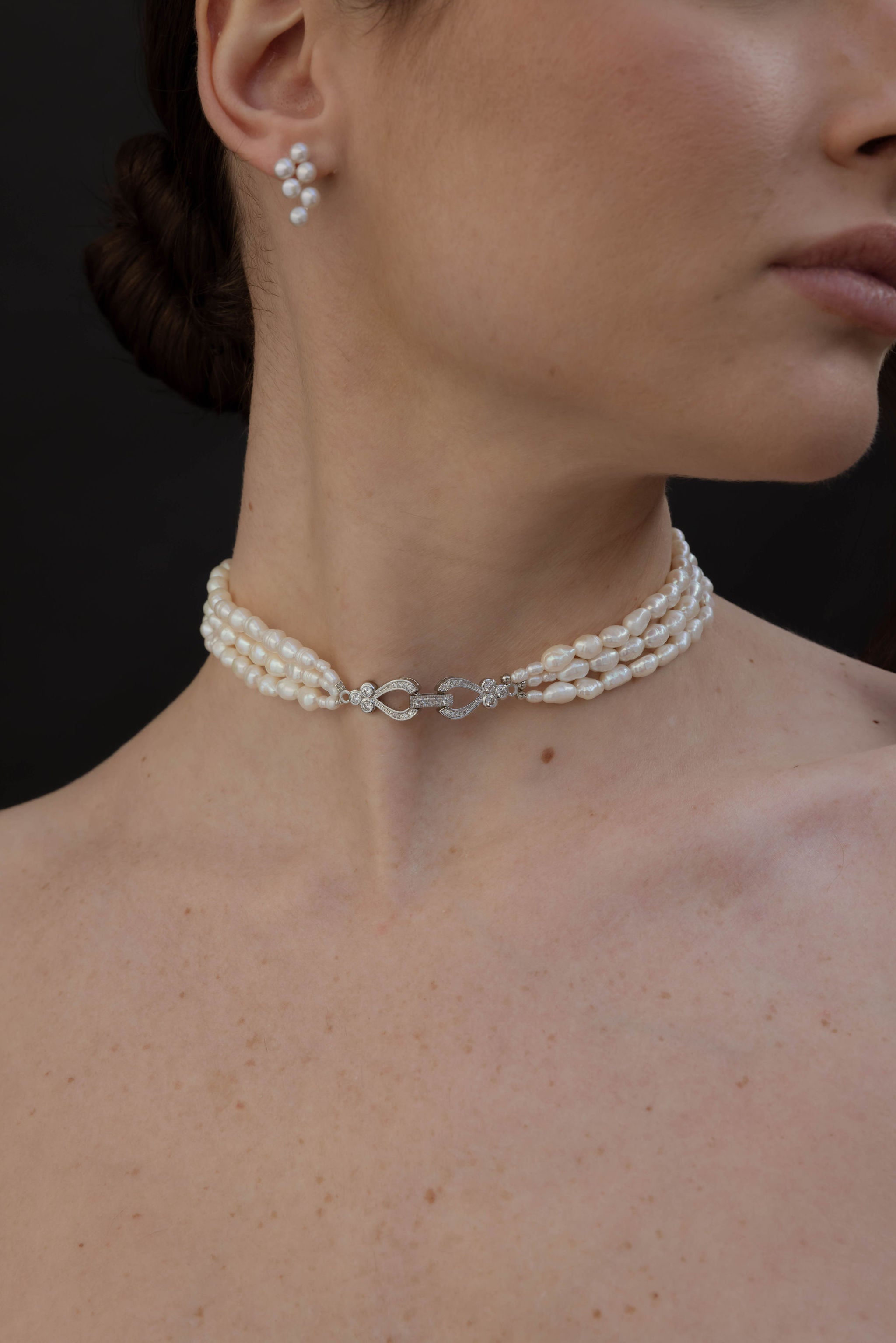 Zoom sur des boucles d’oreilles fines avec six perles et un collier élégant à trois rangs de perles, bijoux minimalistes et raffinés pour mariée.