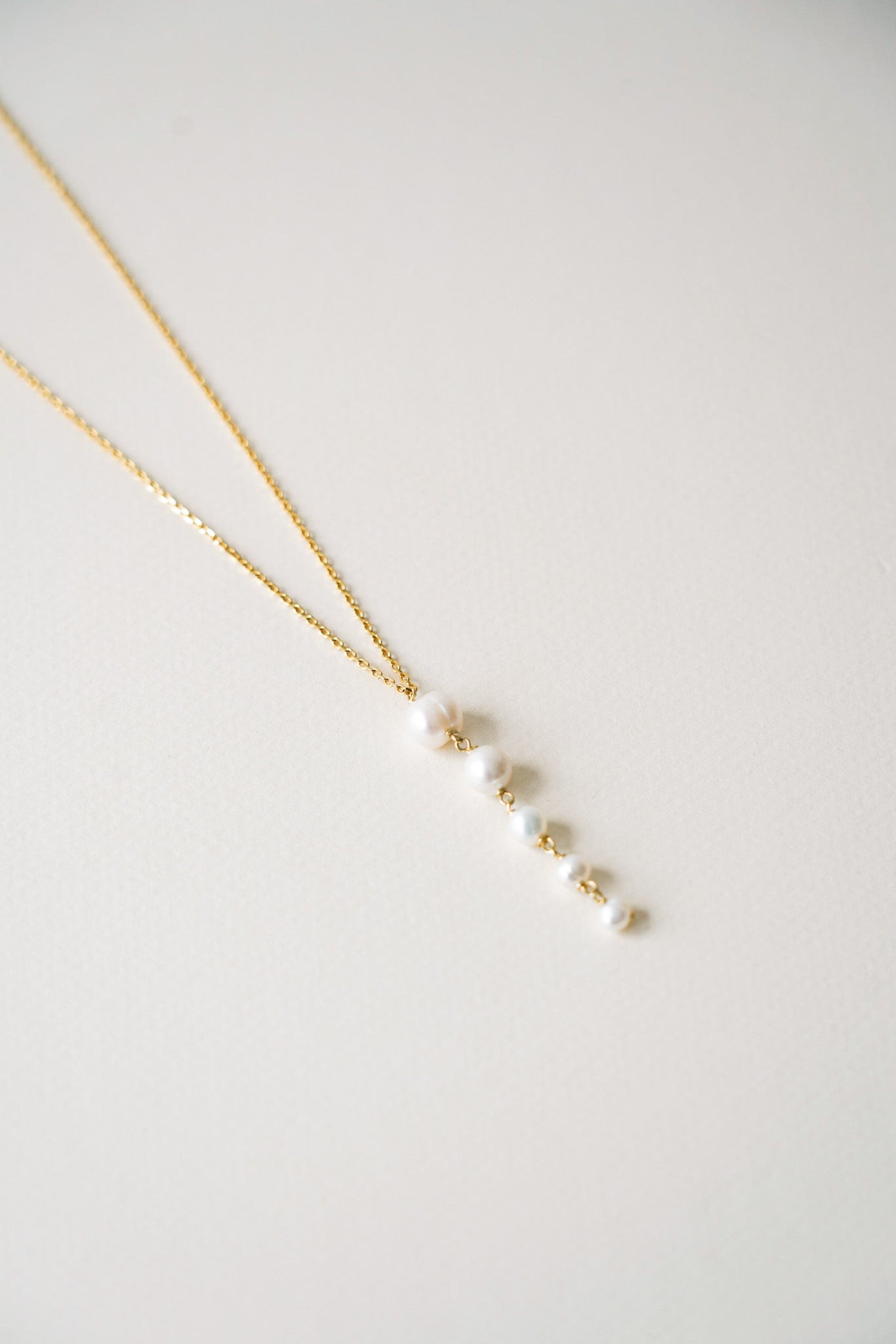 Collier doré délicat, composé de perles de culture disposées en dégradé, allant harmonieusement de la plus grande au centre à la plus petite vers les extrémités. Une pièce élégante et raffinée, parfaite pour un mariage ou une occasion spéciale, apportant une touche subtile de lumière et de douceur au cou.