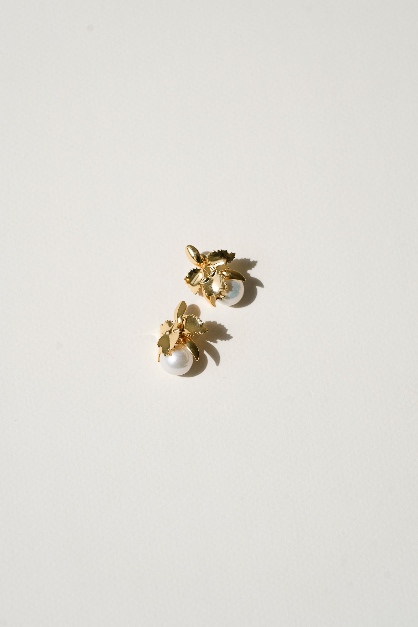 Boucles d'oreilles pour mariée en forme l'orchidée avec une perles naturelle sur un fond beige clair