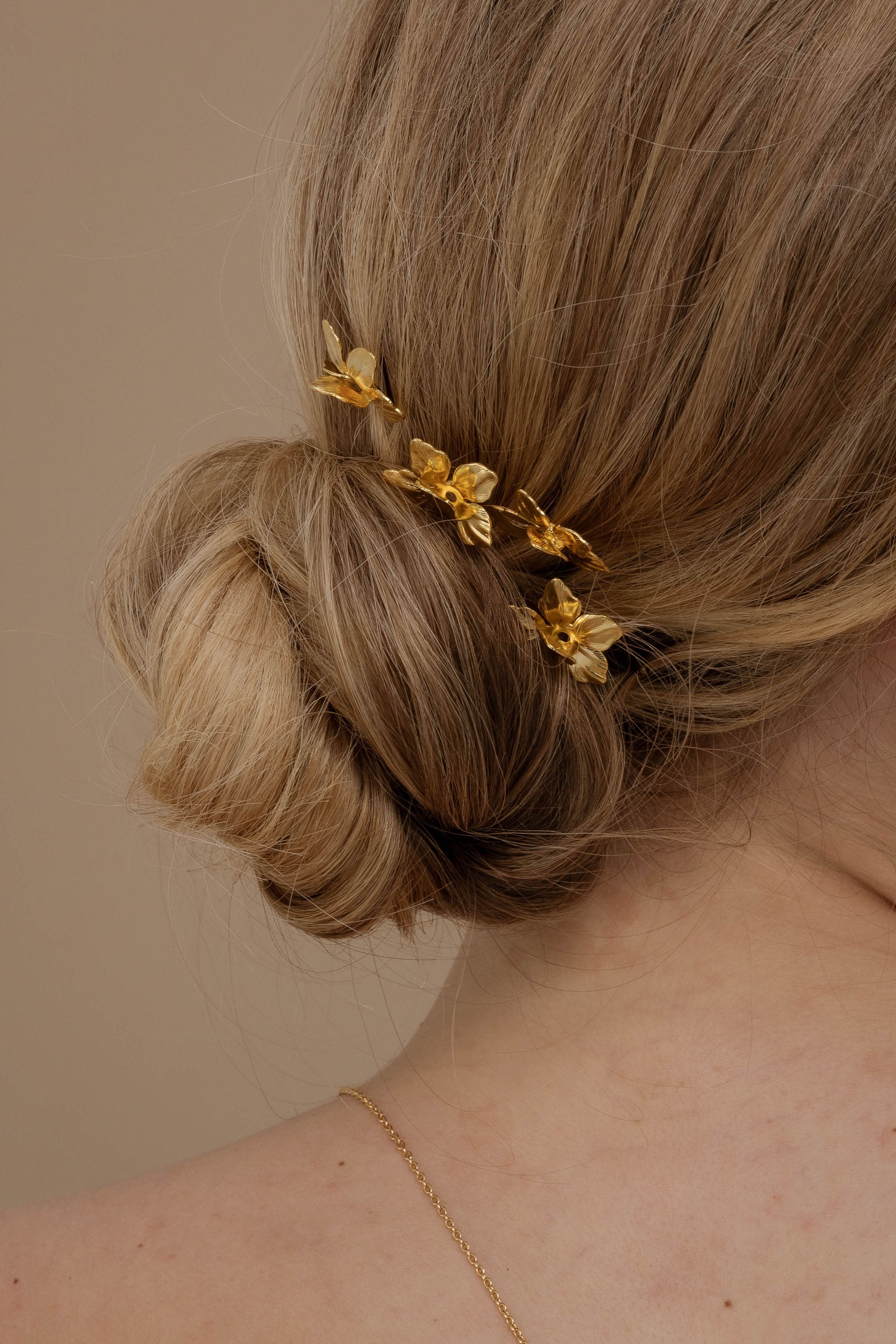 Coiffure chignon avec des petites fleurs dorées sur les un cote de la coiffure