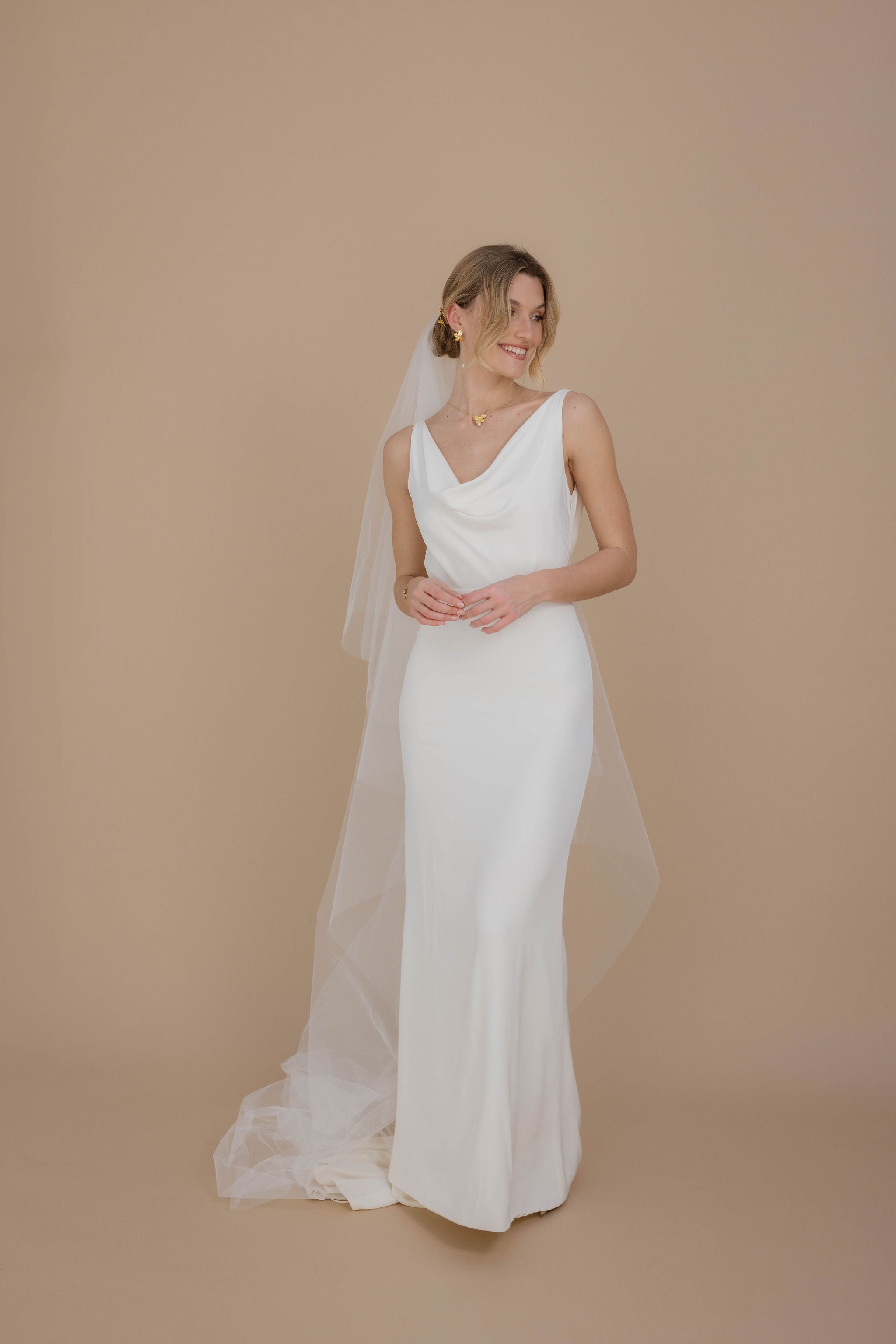 Mariée avec des boucles d'oreilles pendantes et des perles aux bouts, une jolie robe blanche, un chignon élégant et un voile subtil, créant une allure gracieuse et intemporelle