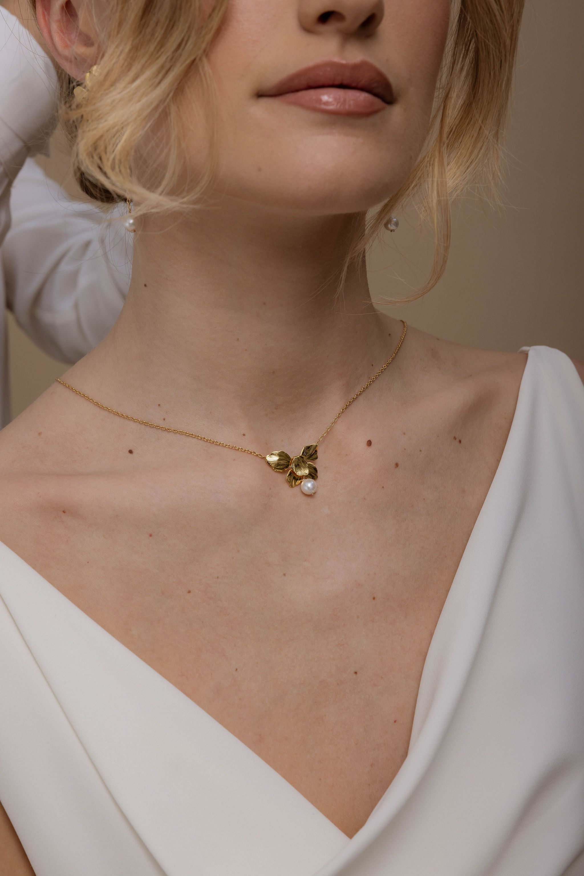 Femme qui porte un collier de mariage avec une fleur et une perle pendante.