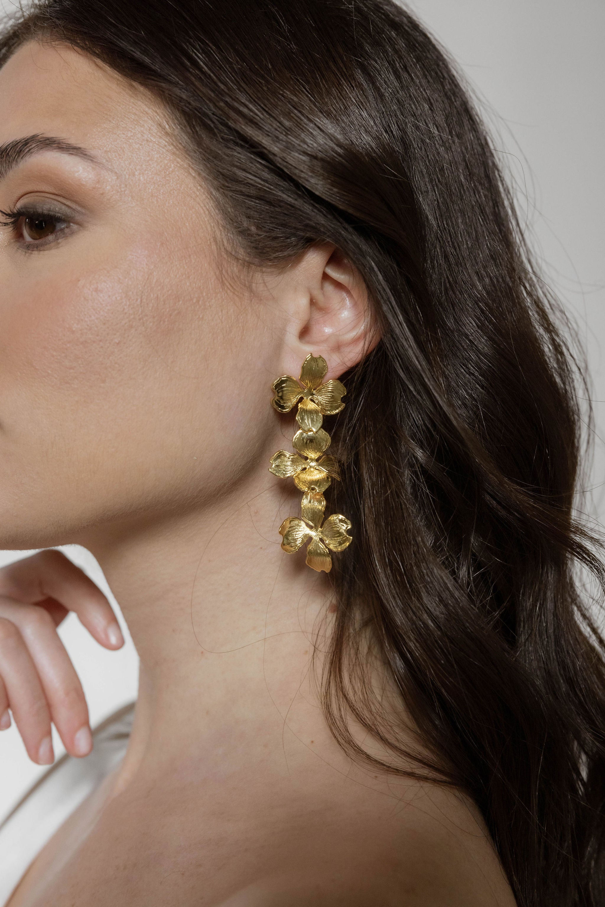 Zoom sur une boucle d’oreille longue florale portée par une mariée, mettant en valeur les détails délicats et la finesse du bijou dans un style romantique.