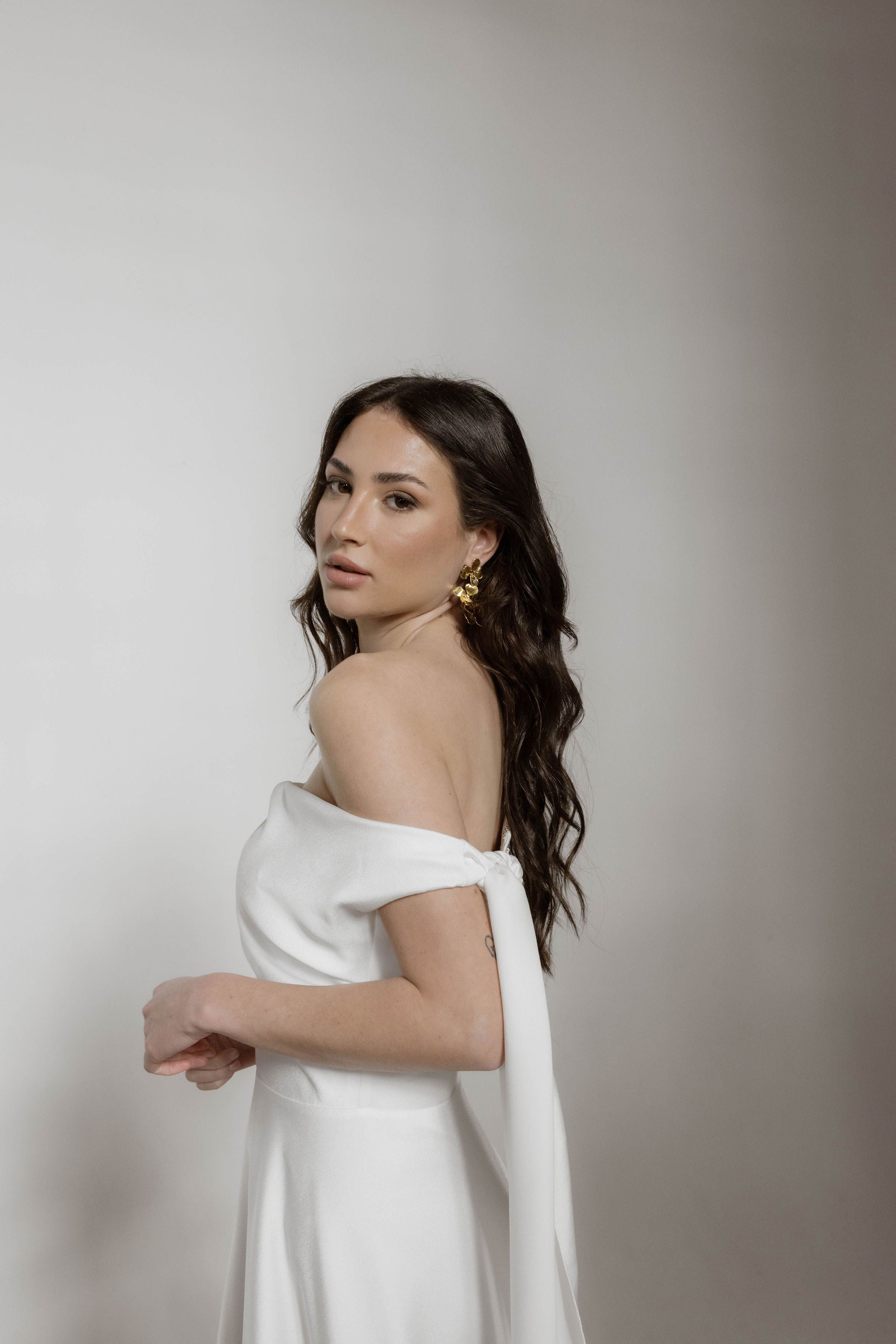 Mariée en jolie robe blanche fluide, cheveux lâchés avec de belles boucles d'oreilles longues florales, apportant une touche d'élégance et de romance à son look