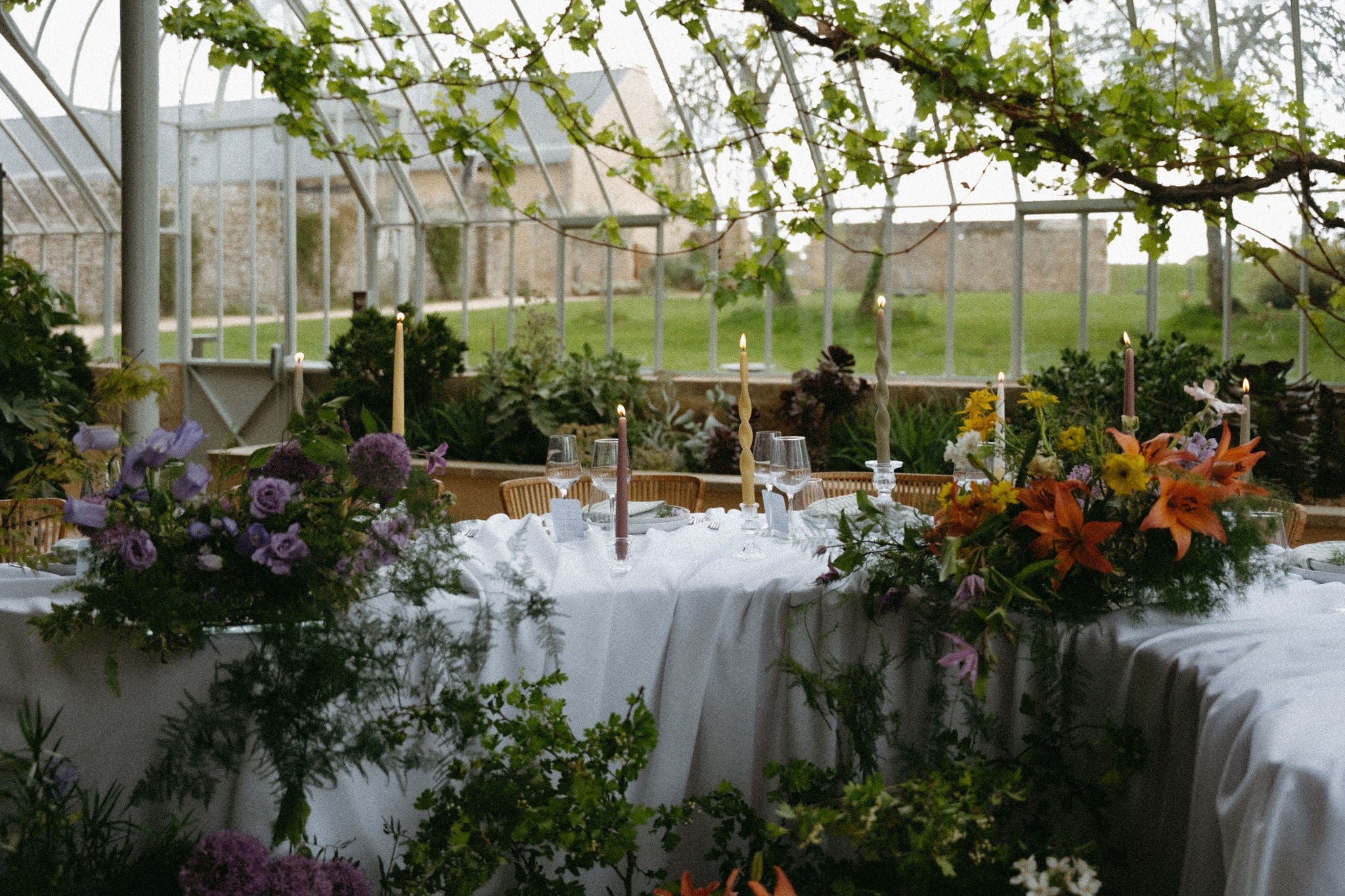 Photo format paysage esthétique d'une table de réception de mariage élégante avec des fleurs, des chandeliers, des bougies, ambiance mariage bohème élégante , arrangement floral mariage, fleurs mariage, décoration mariage château élégante