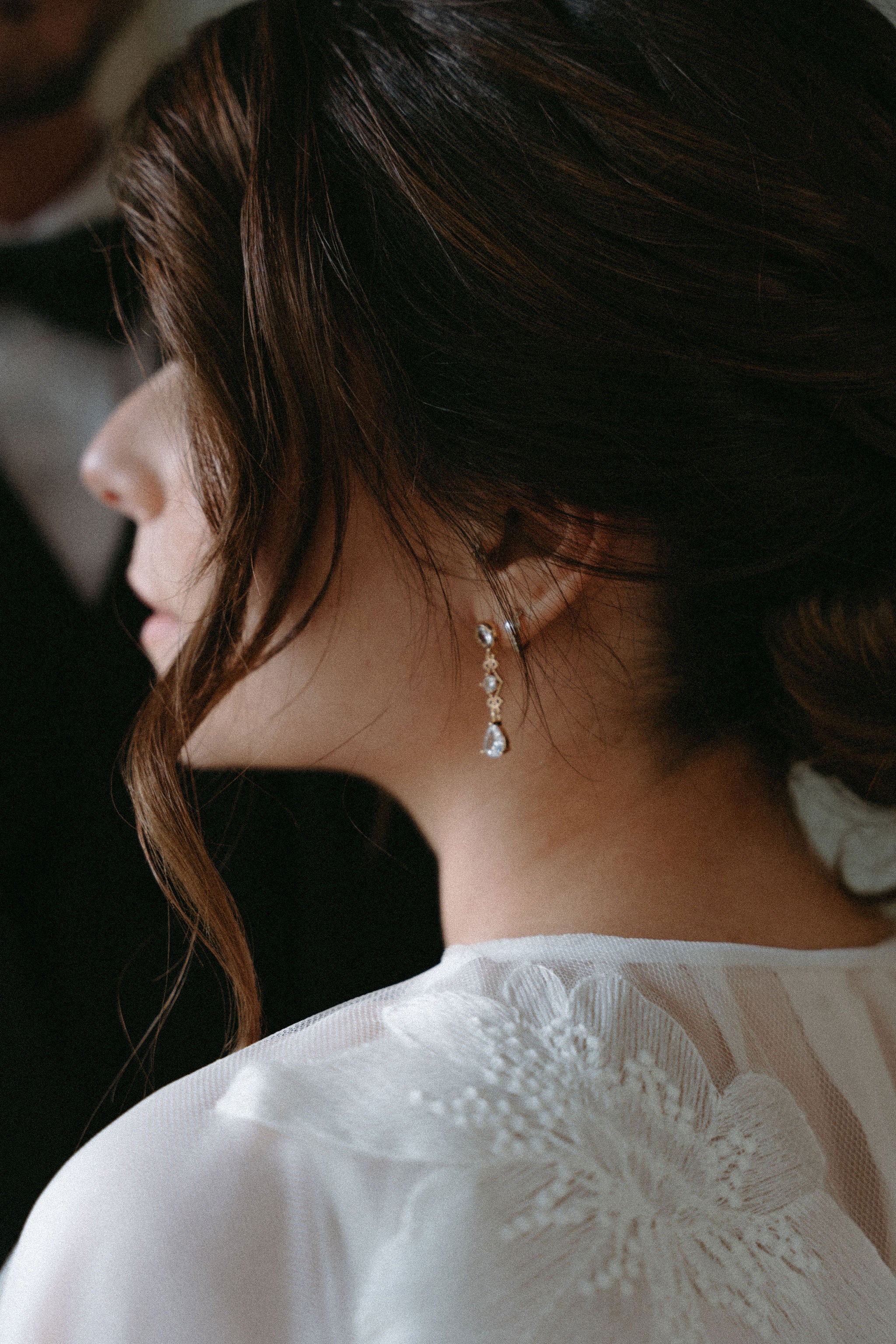 Photo de bijoux de mariage, bijoux de mariée élégants, boucles d'oreilles élégantes zircon Vitoria Atelier Lilac, mariée de profil en robe blanche qui porte des boucles d'oreilles pendantes de mariée