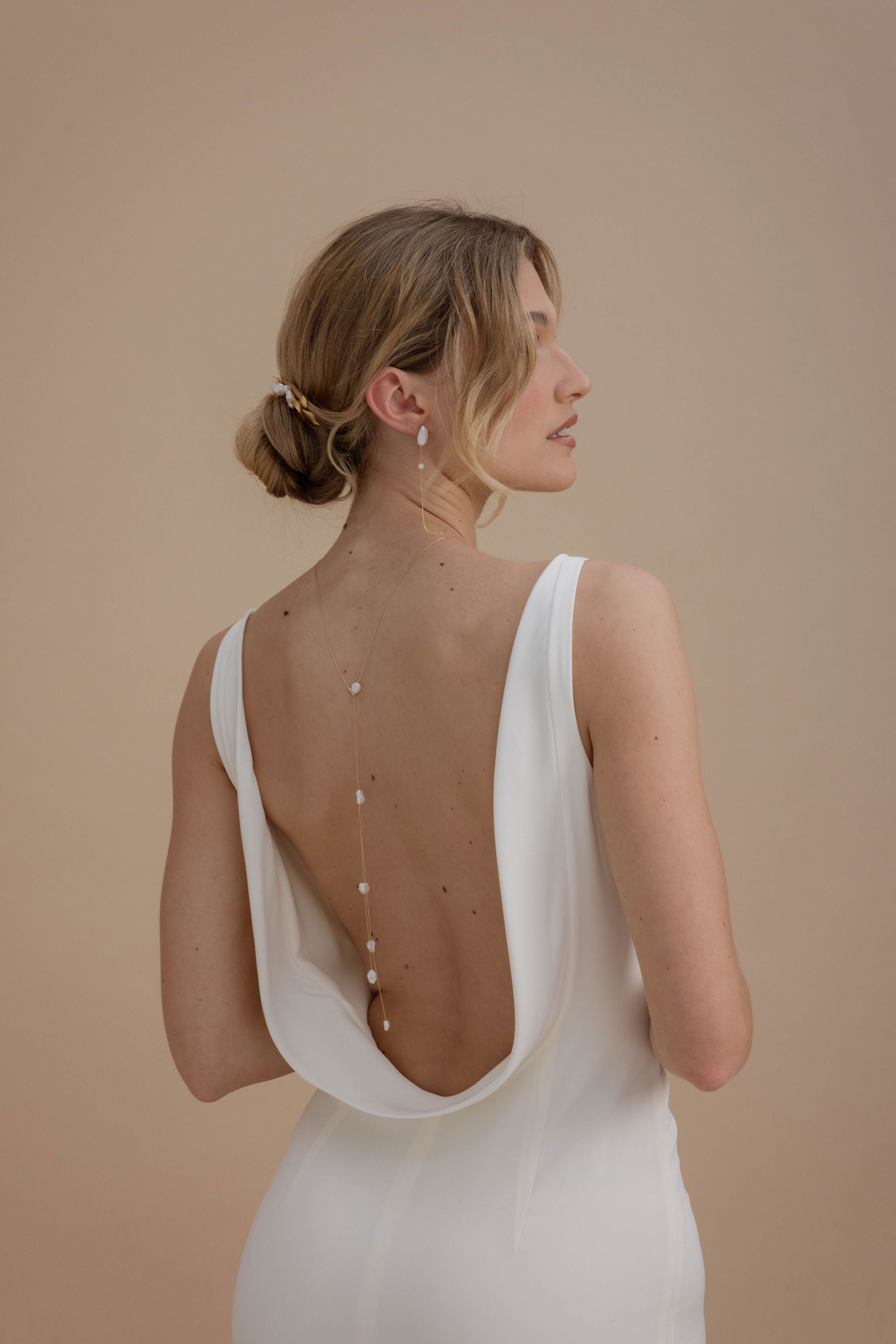 Femme montrant son dos et son bijou de dos de mariage en forme y avec des perles baroque avec ses boucles d'oreilles assorties
