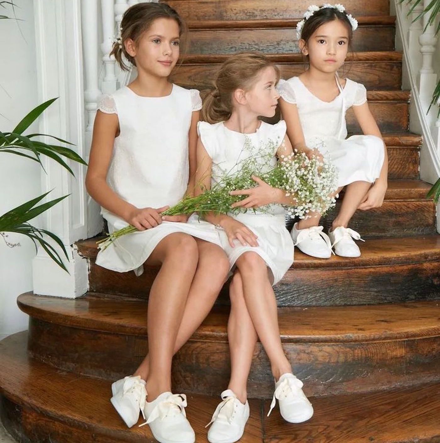 petites filles habillées en robe et chaussures blanches avec des bouquets de fleurs dans les mains