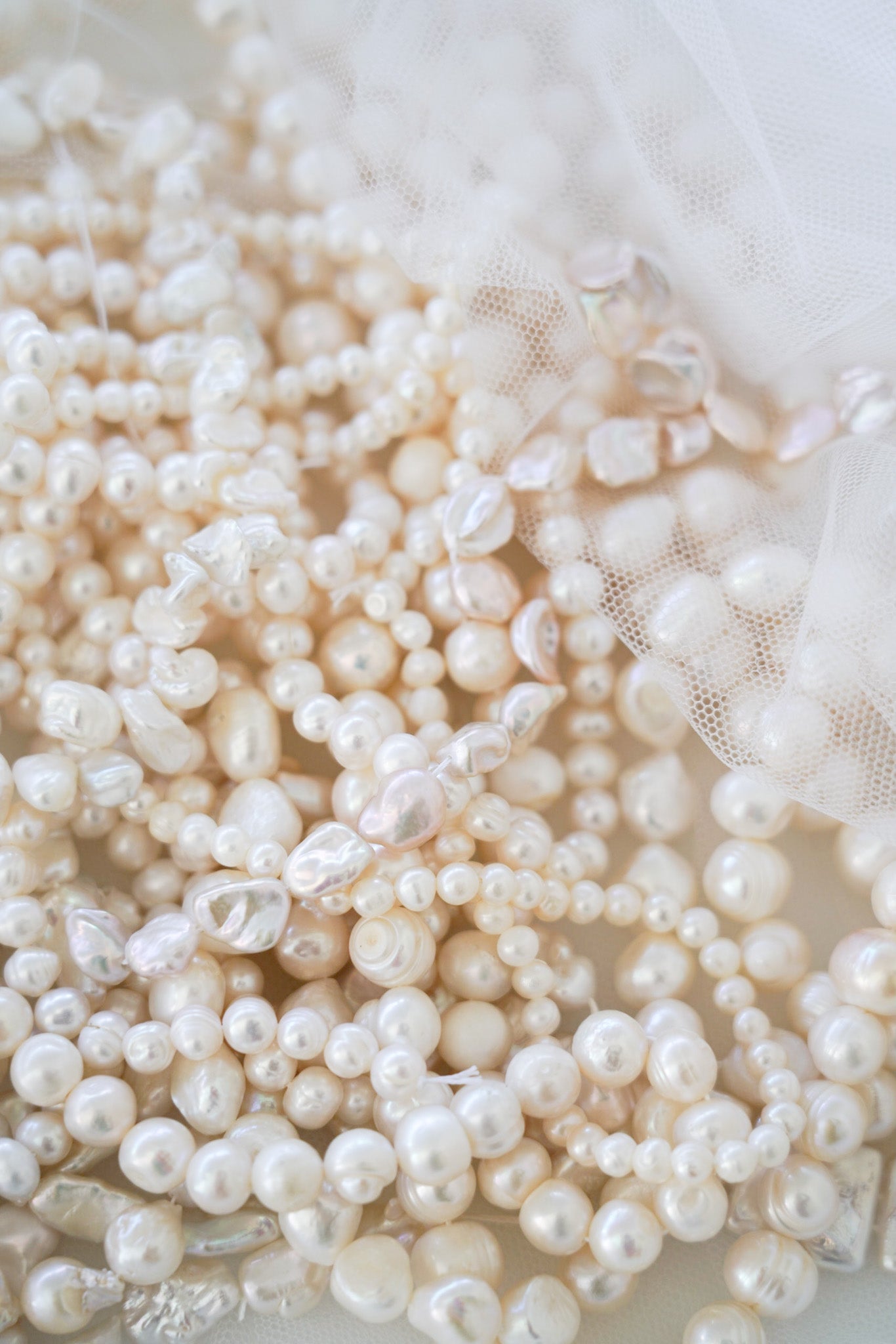 Différentes perles sont posées ensemble, notamment des perles de culture sous diverses formes élégantes et bien brillantes. Leur éclat naturel capte la lumière, mettant en valeur la finesse et la qualité du travail artisanal. Ces perles variées créent un ensemble harmonieux et sophistiqué, alliant texture, forme et luminosité pour un rendu à la fois chic et raffiné.